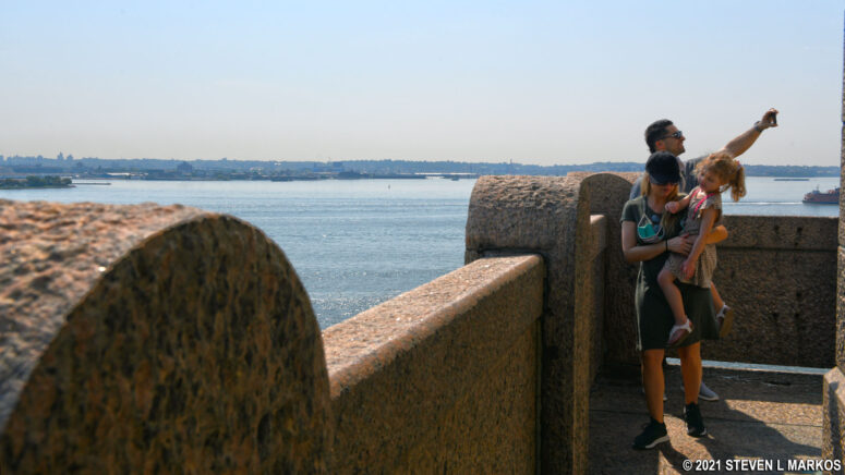 Visitor takes a selfie from the balcony at the top of the Statue of Liberty pedestal