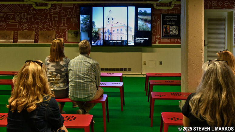 Visitors to Faneuil Hall watch Fighting for Freedom: Lewis Hayden and the Underground Railroad in the lower floor exhibit area