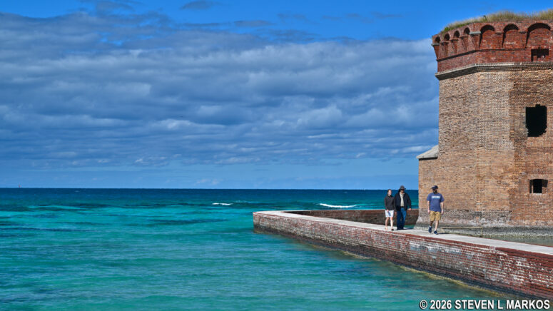Visitors to Dry Tortugas National Park walk along the Fort Jefferson moat wall