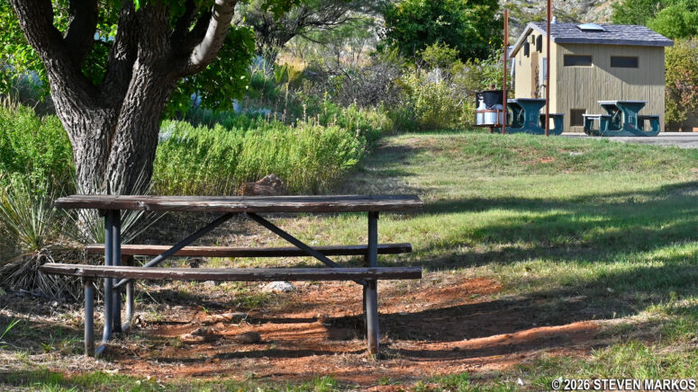 Wooden picnic table under a shade tree at Alibates Flint Quarries National Monument parking lot