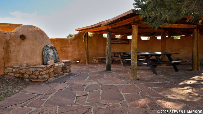 Picnic tables under the shade shelter next to an horno at Pecos National Historical Park